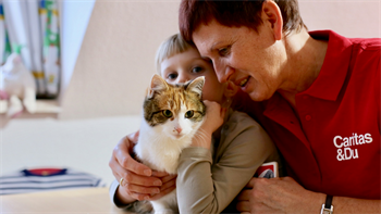 Caritas Mitarbeiterin mit Kleinkind und Katze im Arm